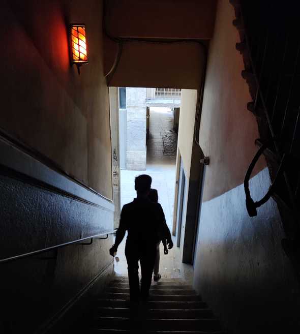 2 people walking through a traboules(passageway) 